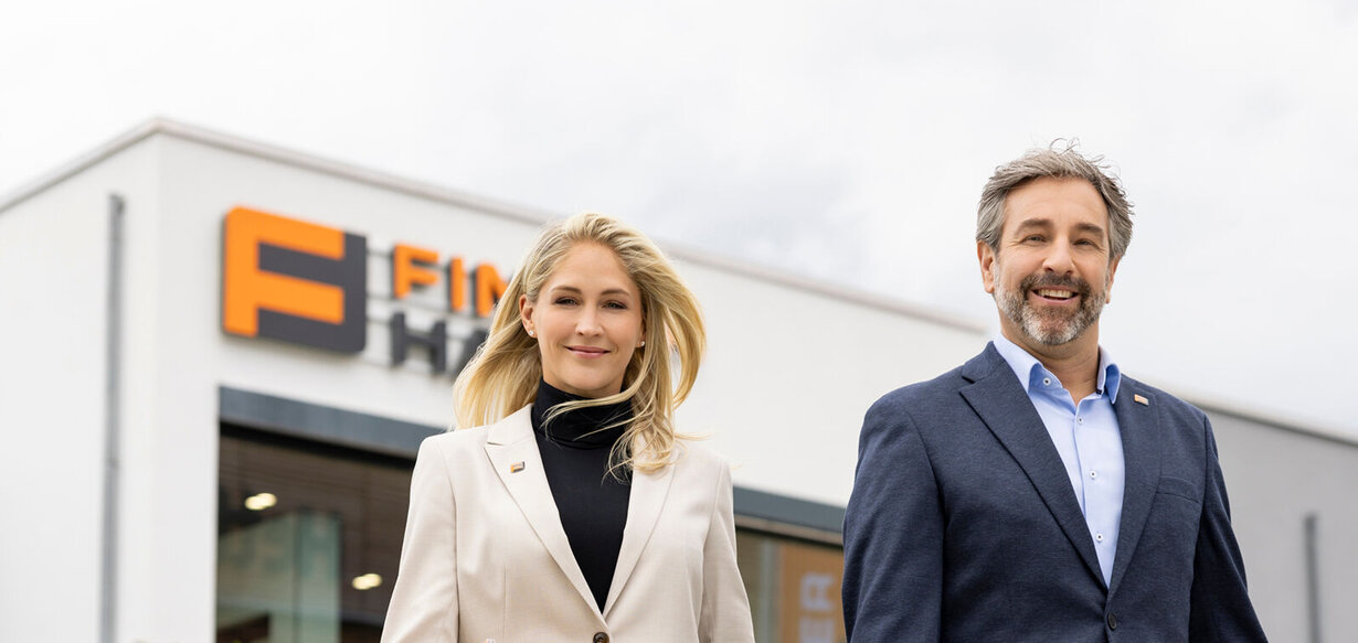 Zwei FingerHaus-Fachberater gehen vor der Zentrale des Unternehmens auf dem Firmengelände.