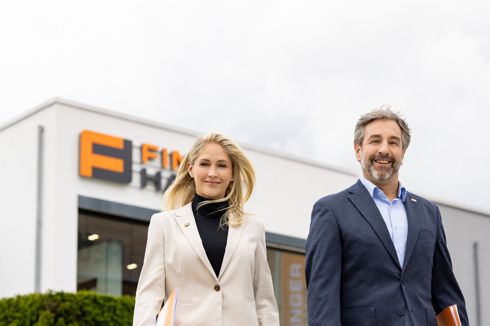 Zwei FingerHaus-Fachberater gehen vor der Zentrale des Unternehmens auf dem Firmengelände.