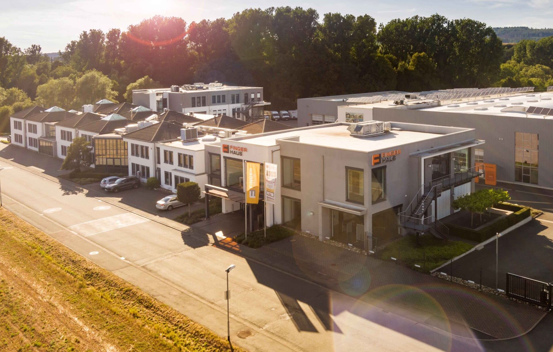 Luftaufnahme des Firmensitzes von FingerHaus in Frankenberg (Eder) bei Sonnenschein, mit Verwaltungsgebäude und Produktionshalle.