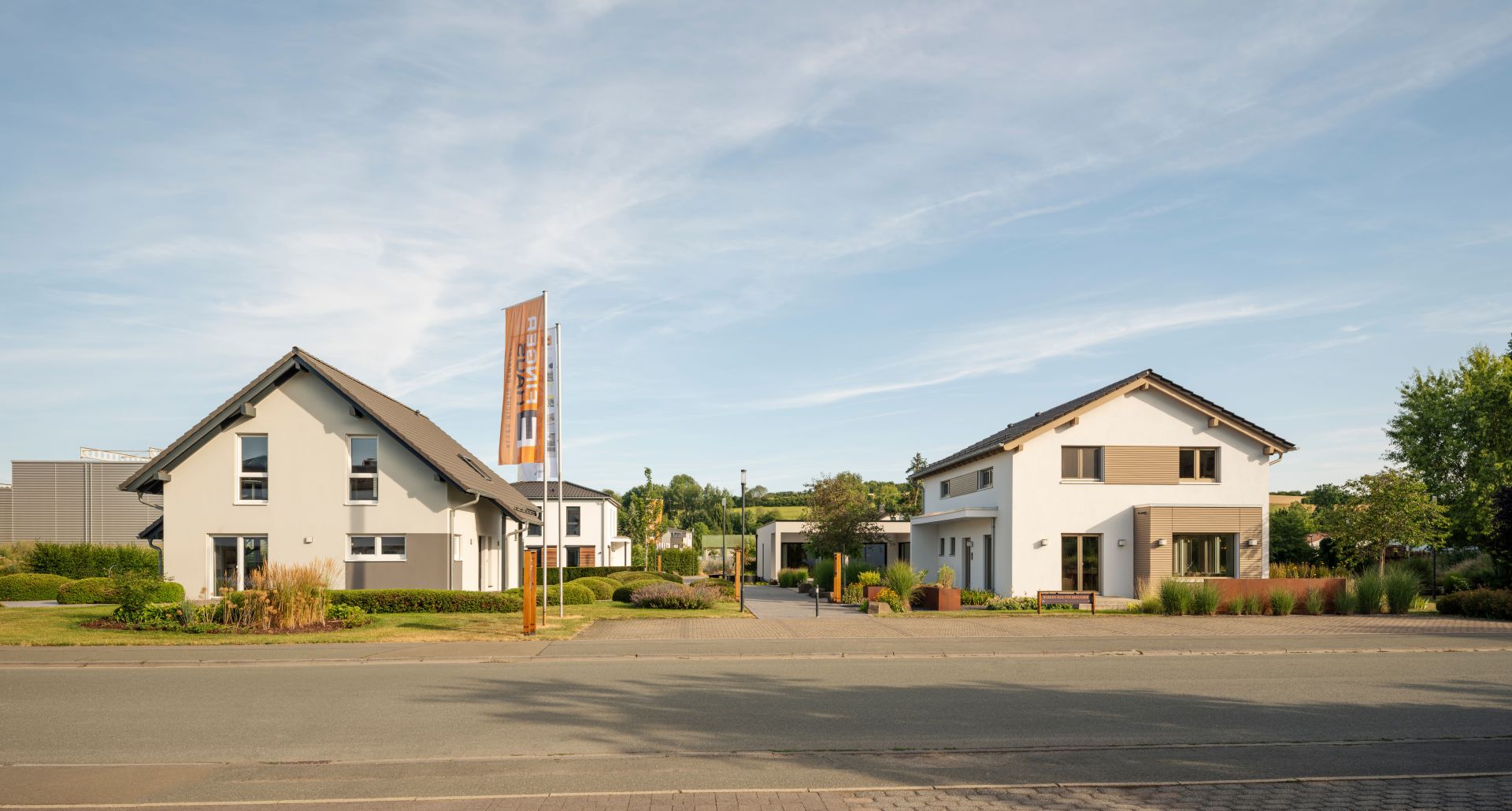 Vier moderne Musterhäuser im FingerHaus Musterhaus-Park mit klaren Fassaden und gepflegten Vorgärten.